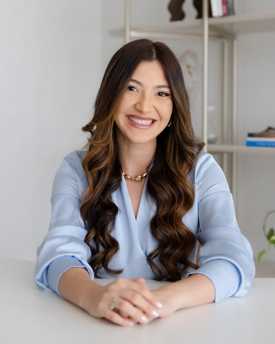 Iara Bianca sorrindo, sentada à mesa do consultório